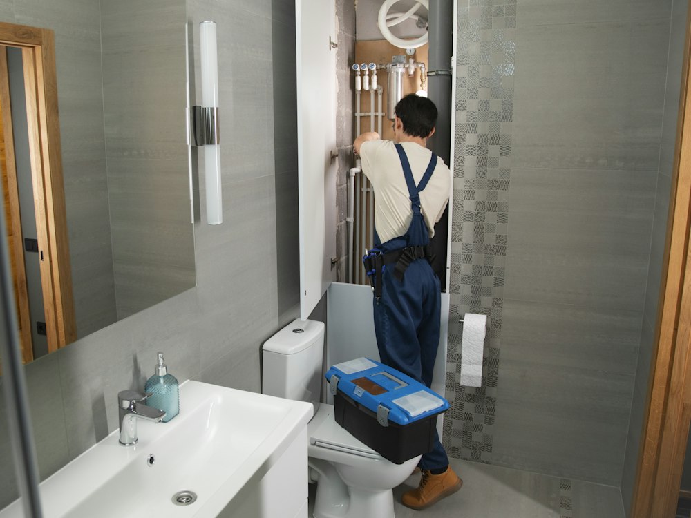Plumber repairing pipes under a sink
