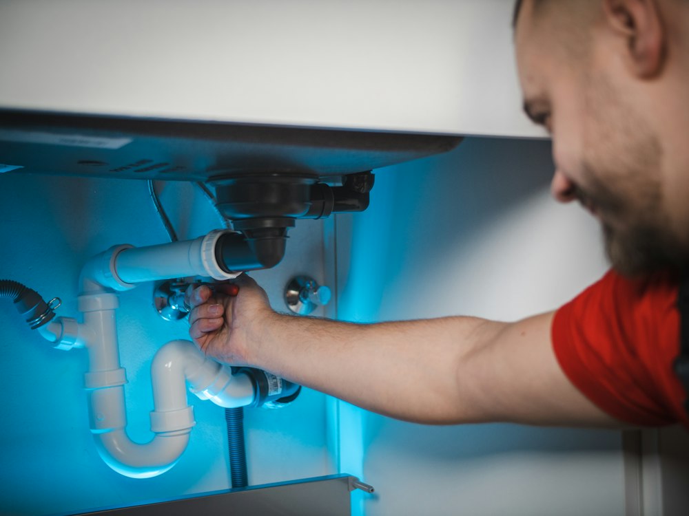 Plumber fixing a pipe under a sink